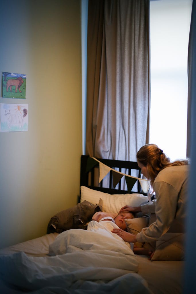 A mother lovingly cares for her young child in a cozy bedroom setting.